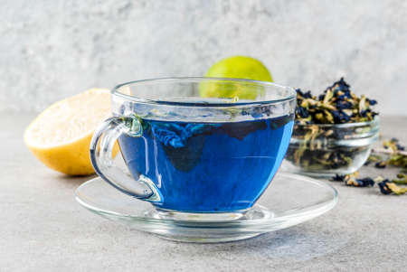 Healthy drinks, organic blue butterfly pea flower tea with limes and lemons, grey concrete background copy spaceの写真素材