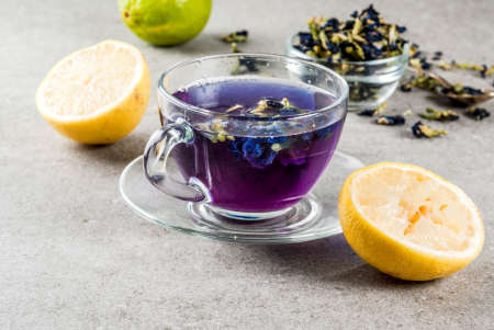 Healthy drinks, organic blue butterfly pea flower tea with limes and lemons, grey concrete background copy space top viewの写真素材