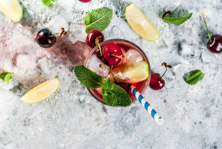 Summer iced refreshment drink, cherry cola lemonade or mojito cocktail in tall glass, on light blue and grey background copy space top viewの写真素材