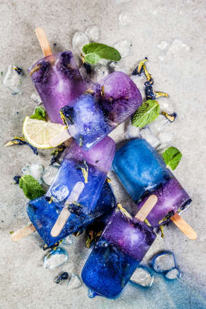 Naturally organic summer sweets, homemade blue and violet ice cream popsicles with butterfly pea...