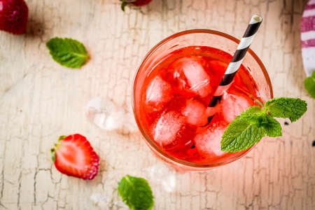Iced strawberry drink, juice, mojito cocktail or liqueur, with fresh strawberries, light beige...