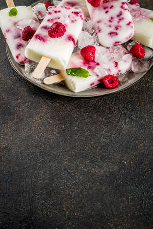 Summer sweet desserts, homemade organic ice cream popsicles from raspberry and yogurt, dark rusty background copy spaceの写真素材