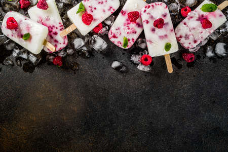 Summer sweet desserts, homemade organic ice cream popsicles from raspberry and yogurt, dark rusty background copy space top viewの写真素材