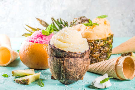 Summer holiday vacation concept, set various tropical ice cream sorbets, frozen juices in pineapple, grapefruit and coconut, light blue concrete background copy spaceの写真素材