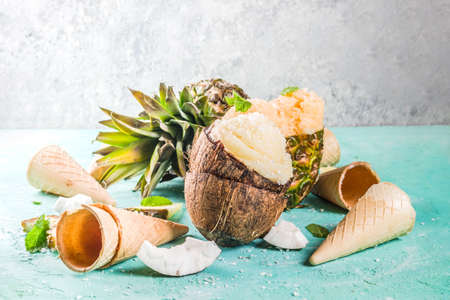 Summer holiday vacation concept, set various tropical ice cream sorbets, frozen juices in pineapple, grapefruit and coconut, light blue concrete background copy spaceの写真素材
