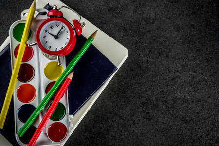 Back to school concept with books, alarm clock, color pencils, chalkboard backgroundの写真素材