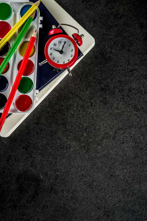 Back to school concept with books, alarm clock, color pencils, chalkboard backgroundの写真素材