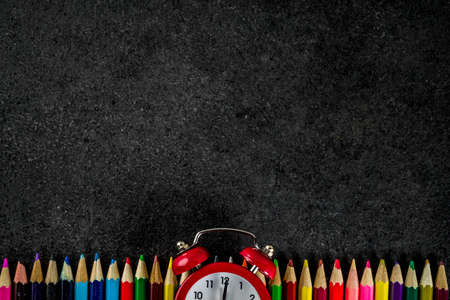 Back to school concept with books, alarm clock, color pencils, chalkboard backgroundの写真素材