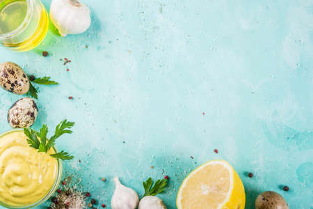 Homemade mayonnaise sauce with ingredients - lemon, eggs, olive oil, spices and herbs, light blue background copy space aboveの写真素材
