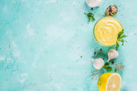 Homemade mayonnaise sauce with ingredients - lemon, eggs, olive oil, spices and herbs, light blue background copy space aboveの写真素材