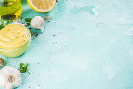 Homemade mayonnaise sauce with ingredients - lemon, eggs, olive oil, spices and herbs, light blue background copy space の写真素材