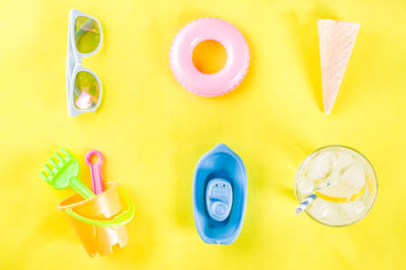 Summer vacation concept with plastic beach kids toys - bucket, scoop, rake, molds boat, lifebuoy toys copy space yellow backgroundの写真素材
