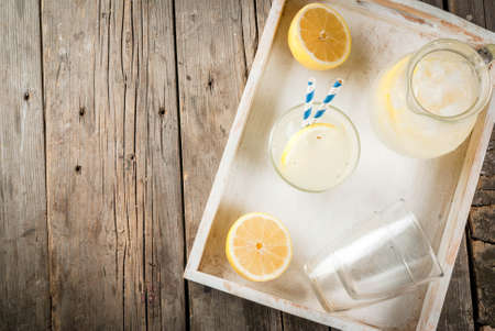 Classic sour and sweet homemade lemonade drink, summer cold iced beverage, rustic wooden background copy space in white tray top viewの写真素材