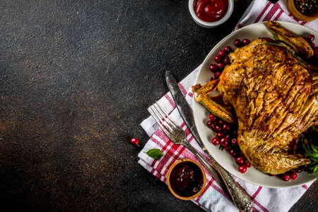 Christmas, thanksgiving food, baked roasted chicken with cranberry and herbs, served with fried vegetables and sauces on dark rusty table, copy space top viewの写真素材