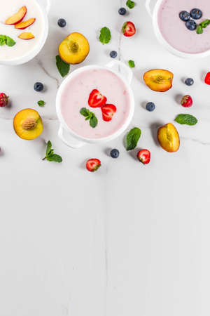 Summer healthy diet dinner, vegan food, dessert, various sweet creamy fruit & berry soups - strawberry, peach, blueberry, white marble background  copy space aboveの写真素材
