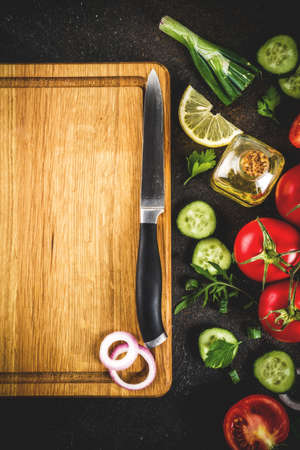 Cooking background, fresh salad ingredients, italian cuisine - tomatoes, olive oil, lemon, cucumbers, arugula, parsley, onions, with knife and cutting board, Dark rusty background copy space top viewの写真素材