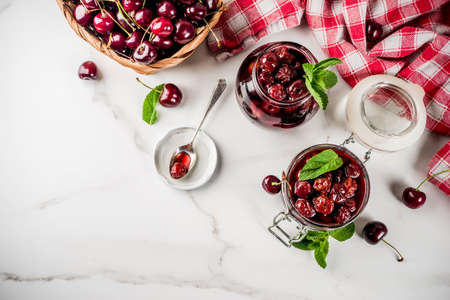 Homemade preserved cherry and mint jam, with fresh cherries on white marble background copy space top viewの写真素材