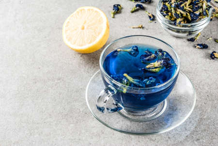 Healthy drinks, organic blue butterfly pea flower tea with limes and lemons, grey concrete background copy spaceの写真素材