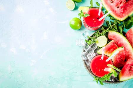 Fruity summer cold drink, homemade watermelon juice or smoothie served with lime and fresh mint leaves, light blue trendy background copy space top viewの写真素材