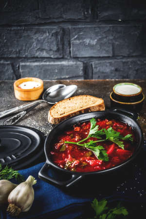 Ukrainian Russian traditional hot dish - borsch soup, with greens, garlic, rye bread, on a dark table,の写真素材