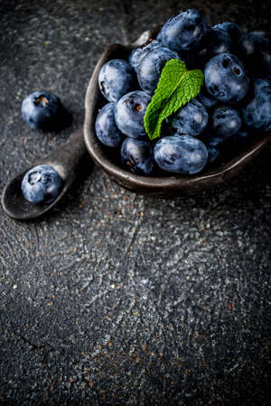 Raw fresh blueberries in small black bowl, dark rusty background copy spaceの写真素材