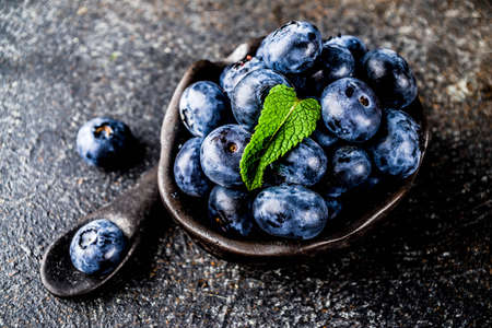 Raw fresh blueberries in small black bowl, dark rusty background copy spaceの写真素材