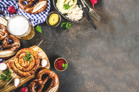 Oktoberfest food menu, bavarian sausages with pretzels, mashed potato, sauerkraut, beer bottle and mug, dark rusty background copy space top viewの写真素材