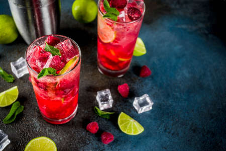 Iced summer drink cocktail, Raspberry and lime lemonade with fresh mint and lime, dark blue rusty background copy spaceの写真素材