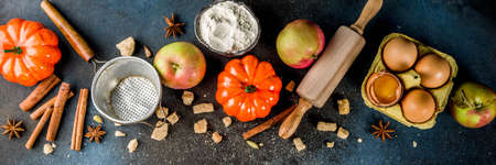 Sweet autumn baking cooking background with flour, rolling pin, decorative pumpkins, apples, cinnamon spices with anise cardamom sugar. Dark blue rusty background top view copy space bannerの写真素材