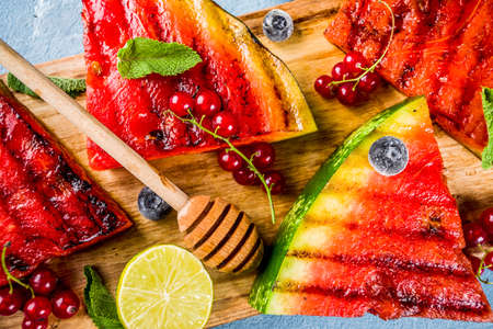 Summer bbq concept, grilled watermelon with berries, mint, lime and honey, light blue background copy space aboveの写真素材