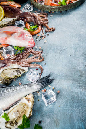 Fresh raw seafood squid shrimp oyster mussels fish with spices of herbs lemon on a light blue background copy spaceの写真素材