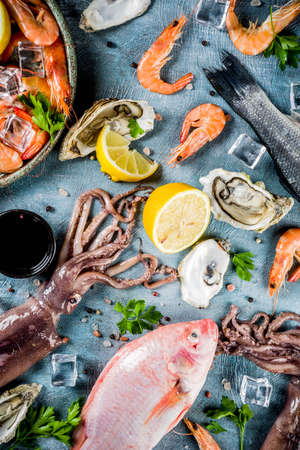 Fresh raw seafood squid shrimp oyster mussels fish with spices of herbs lemon on a light blue background copy space top viewの写真素材