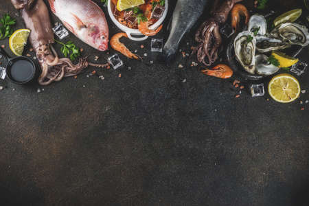 Fresh raw seafood squid shrimp oyster mussels fish with spices of herbs lemon on dark rusty...