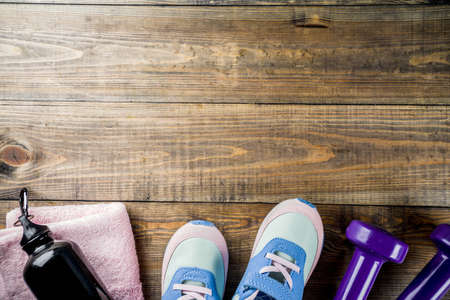 Fitness concept background with dumbbells, sneakers, a towel, a bottle of water, wooden background, copy spaceの写真素材
