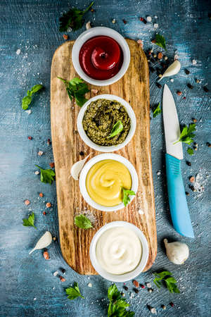 Set of four classic sauces - ketchup, mayonnaise, mustard, pesto - with herbs and spices. Blue...