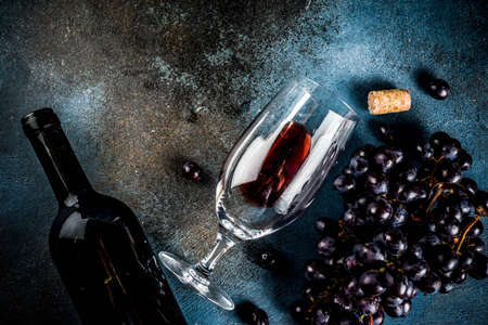 Red wine bottle with glass and grapes, dark background copy space top view selective focusの写真素材