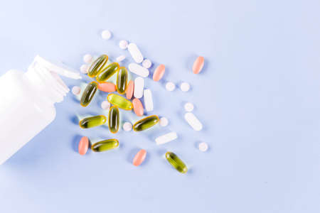 Medical and healthcare concept - different shape pills, thermometer on blue background, top viewの写真素材