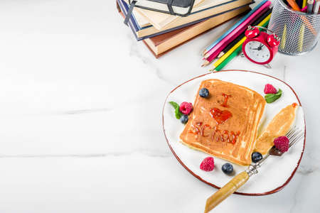 Back to school kids breakfast concept, pancakes with raspberry jam - I love school, on white marble...
