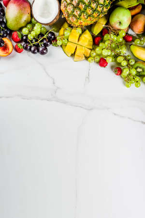 Various tropic fruits, summer vitamins concept, coconut, pineapple, grapes, peach, nectarine, strawberry, apples, mango, banana. top view copy spaceの写真素材
