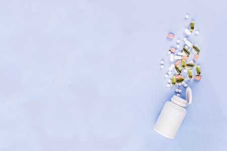 Medical and healthcare concept - different shape pills, thermometer on blue background, top viewの写真素材