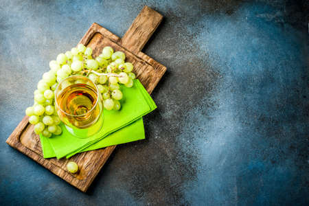 White wine glass with a branch of grapes, on a marble white table, copy spaceの写真素材