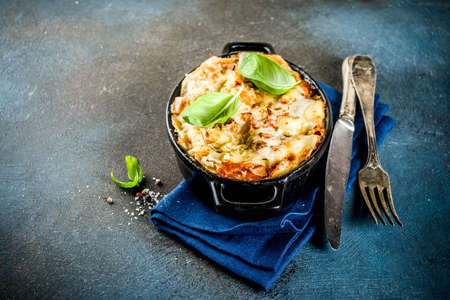 Traditional italian food, homemade lasagna with fresh basil, dark blue background copy spaceの写真素材