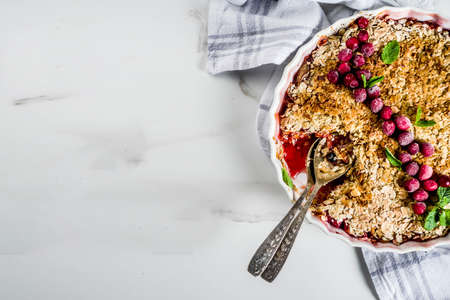 Traditional autumn winter pastries, homemade pie crumble with apples and cranberries, on a white marble table, copy space for textの写真素材