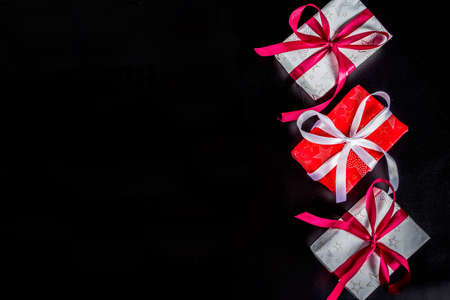 Christmas background for greeting card, with Christmas tree branch and gifts boxes with ribbons, on black background top view copy space for textの写真素材