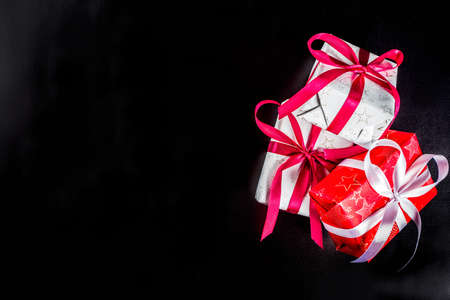 Christmas background for greeting card, with Christmas tree branch and gifts boxes with ribbons, on black background top view copy space for textの写真素材