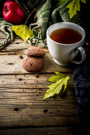 Autumn theme background, old wooden vintage planks boards, with plaid, sweater and autumn yellow leaves, tea cup, apples and chocolate chip cookies, with smartphone top view copy spaceの写真素材