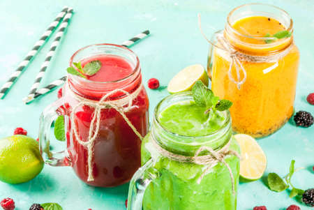 Healthy fresh fruit and veggie smoothies with ingredients on light blue concrete table, copy space