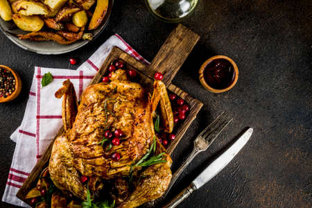 Christmas, thanksgiving food, baked roasted chicken with cranberry and herbs, served with fried vegetables and sauces on dark rusty table, copy space aboveの写真素材