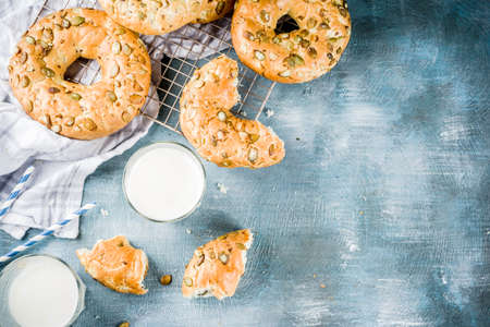 Healthy breakfast concept, home made cereal bagels with milk glass, on blue background copy space