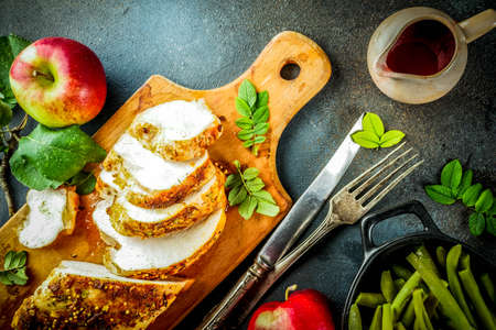Thanksgiving holiday table with traditional festive food - turkey, pumpkin pie, pumpkins, green beans, cranberry sauce, corn, autumn apples, dark rusty table, top view space for textの写真素材